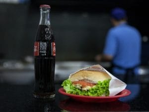 Hambúrguer servido no pratinho colorido e garrafinha de vidro são marcas da lanchonete. Foto: Marcelo Brandt / G1.