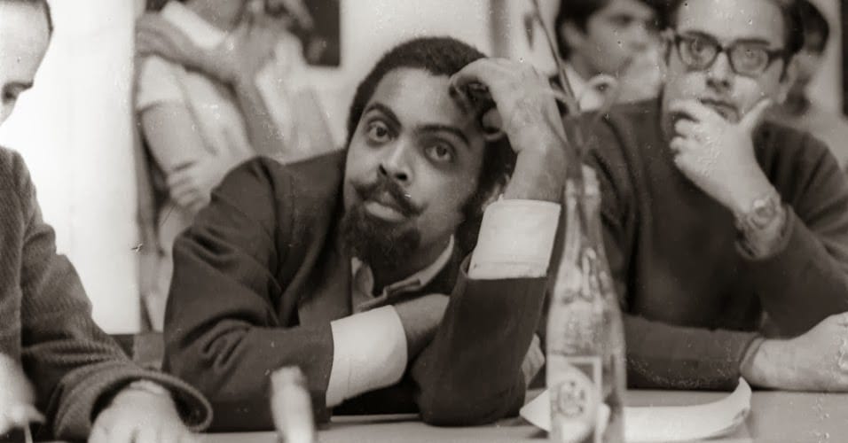 Debate na Faculdade de Arquitetura e Urbanismo (FAU) de São Paulo, em 6 de junho de 1968. Caetano Veloso, Gilberto Gil (foto), Torquato Neto e os poetas concretos Augusto de Campos (foto) e Décio Pignatari.