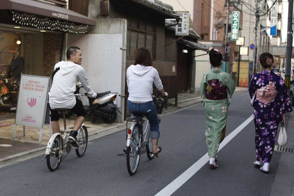 Ciclistas e ‘gueixas’ no centro de Kioto (Japão). Foto: Yvan Cohen / Getty Images.