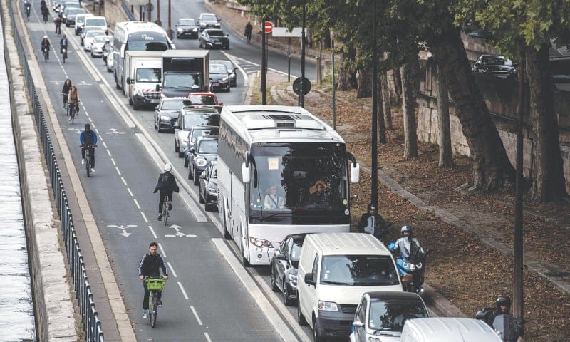 Ciclistas passam ao lado de congestionamento na hora do rush, em Avenida de Paris. Foto: Le Figaro.