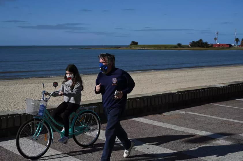 Um homem e sua filha, ambos com máscaras, se exercitam na 'Rambla' de Montevidéu, Uruguai no último 14 de maio de 2020. Eitan Abramovich / AFP .