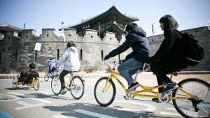 Jovens da cidade de Suwon fazem tour de bicicletas perto da fortaleza Hwaseong, durante evento "Independência sem carros". Foto: Prefeitura de Swon.
